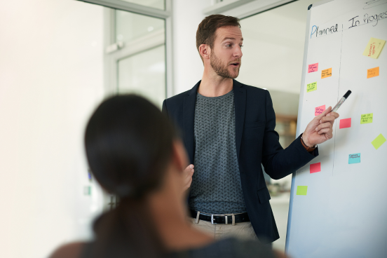 Person pointing at a post-it note on a whiteboard