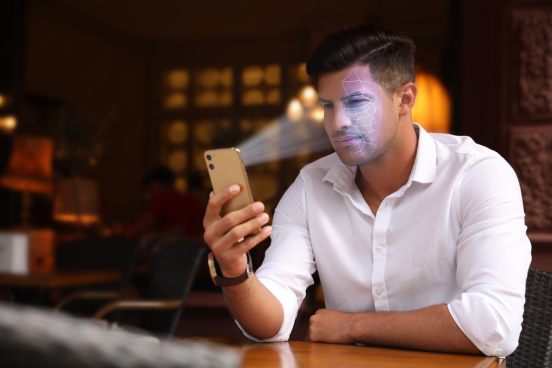 A person holding a phone and trying to unlock it using face scan